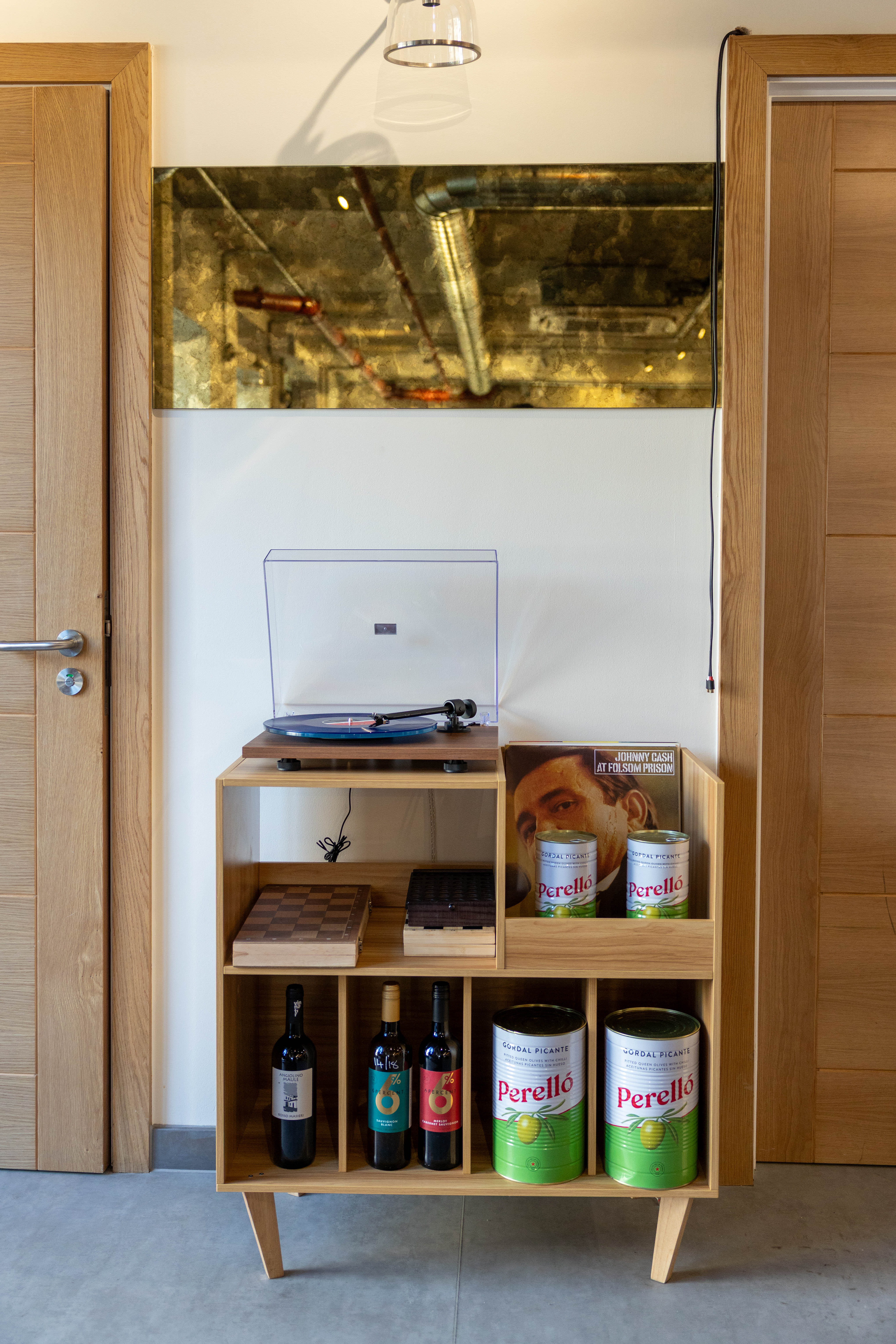 Freestanding oak cabinet between two doorways at Koncept Coffee and Wine, with an antiqued brass panel above it