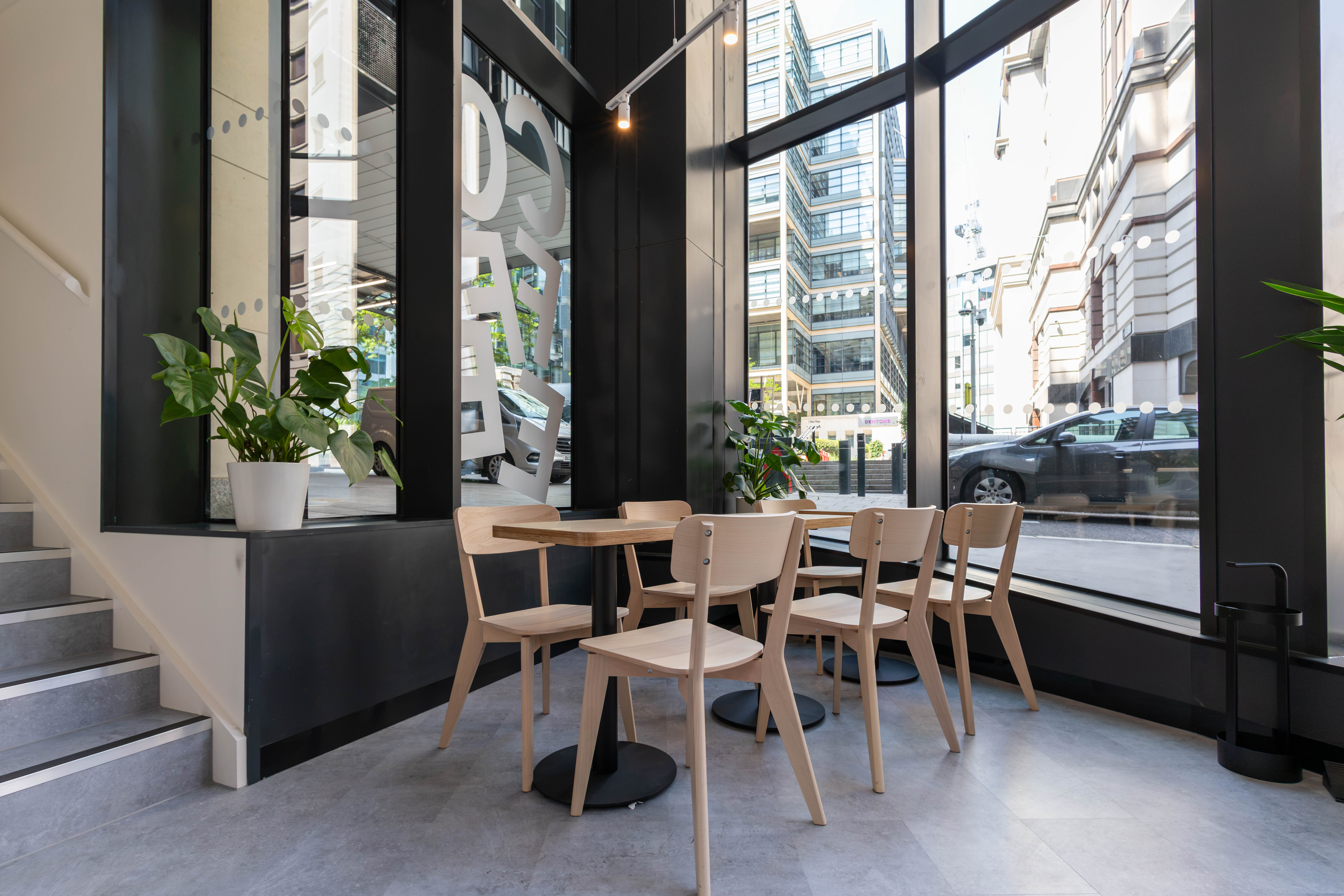 Ash chairs and plywood tables at the full-height glazing onto Fleet Place